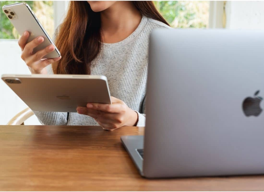 Woman using iPhone, iPad and MacBook