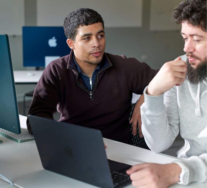 A young adult supporting a student with their Mac.